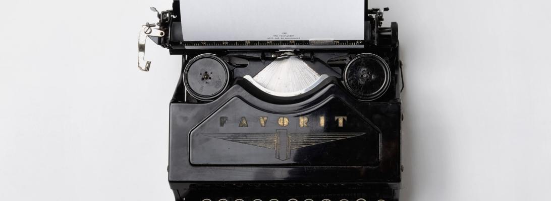 Black typewriter with white paper and a white background